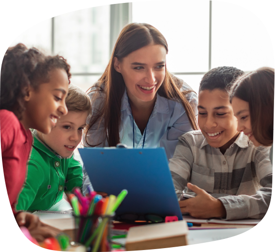 Teacher engaging with diverse group of elementary school students gathered around a laptop during a classroom activity