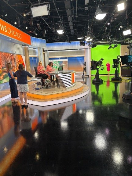 CBS Chicago newsroom during LetMeFail media appearance, with anchors preparing on set and green screen visible in background.